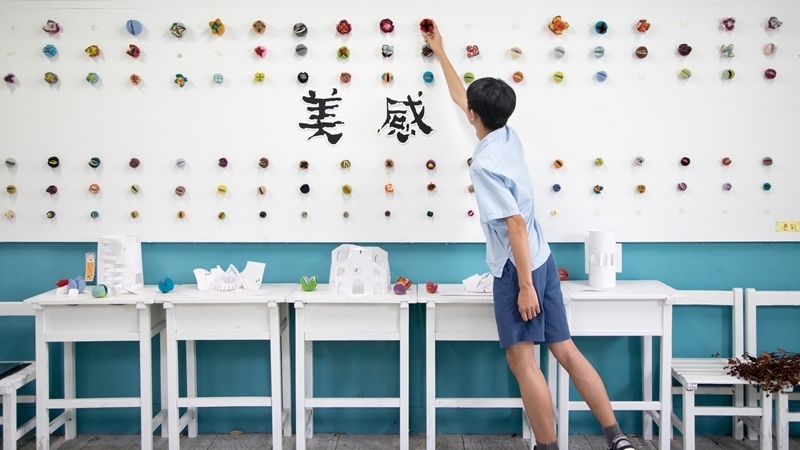 學生穿藍色制服將花放置在牆面上
