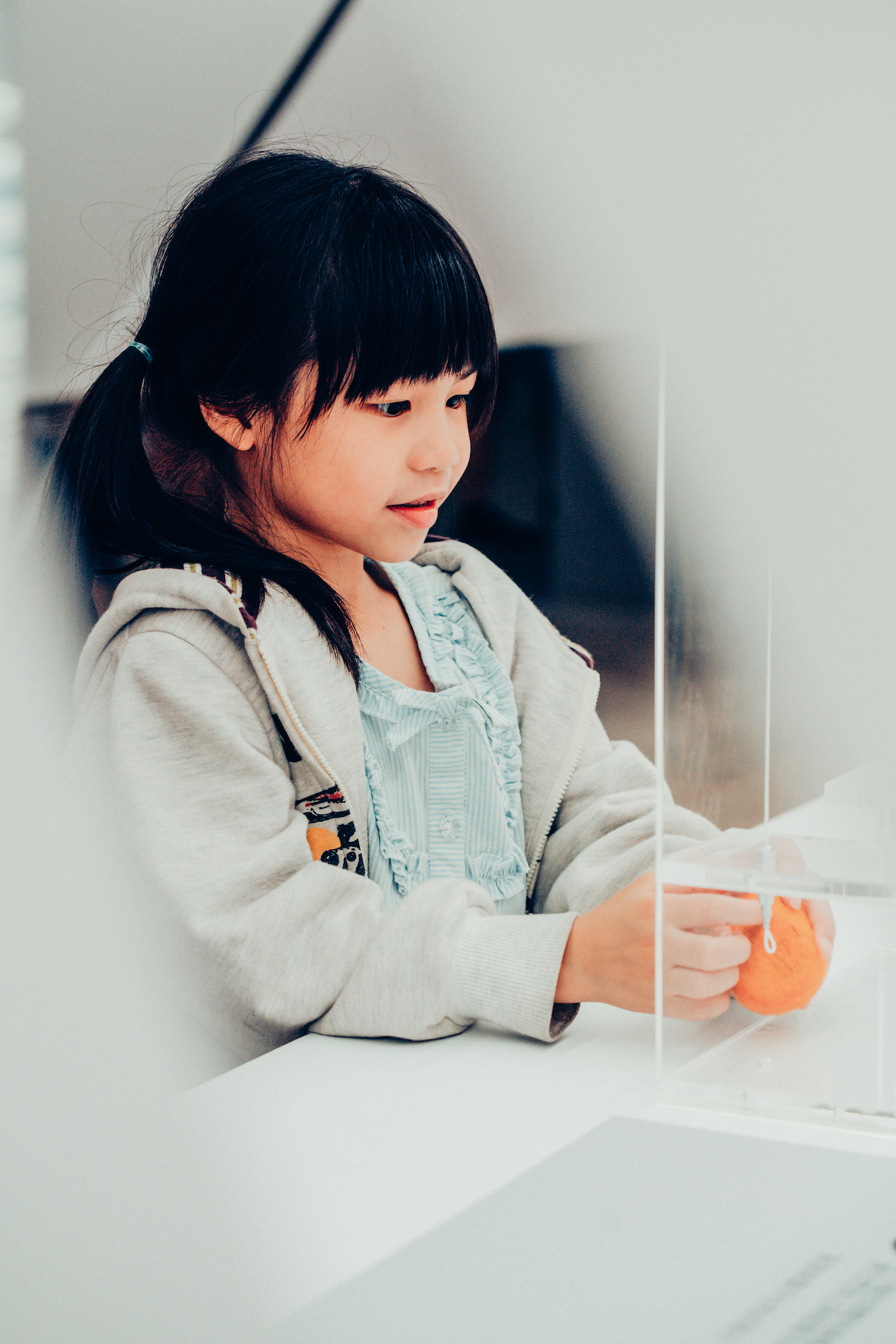 「美角，生活中的每一課2.0」成果展活動側拍，綁著馬尾的小女孩在展台上玩教具。