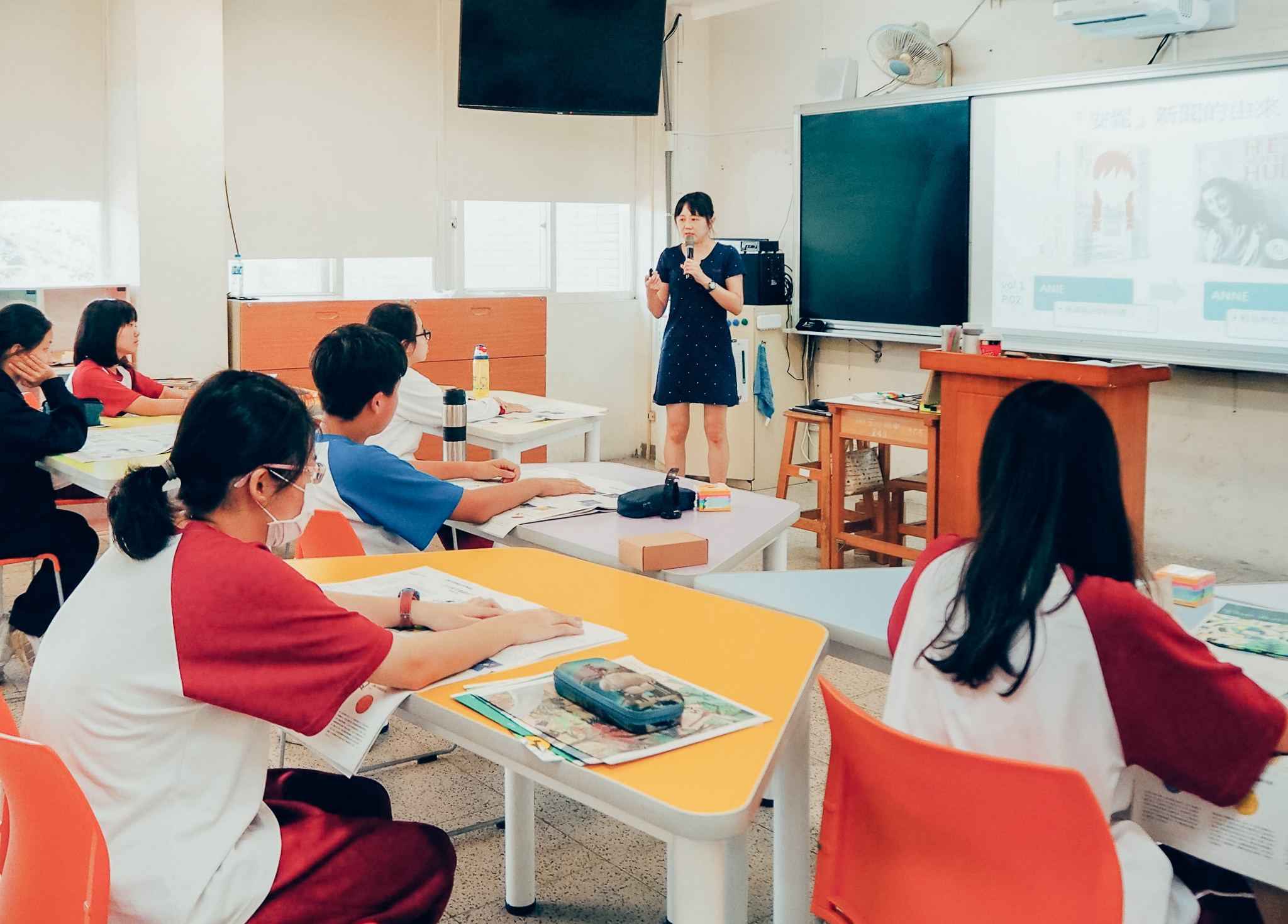 官意千老師在學校教授美感課程，同學的桌子是梯形的。