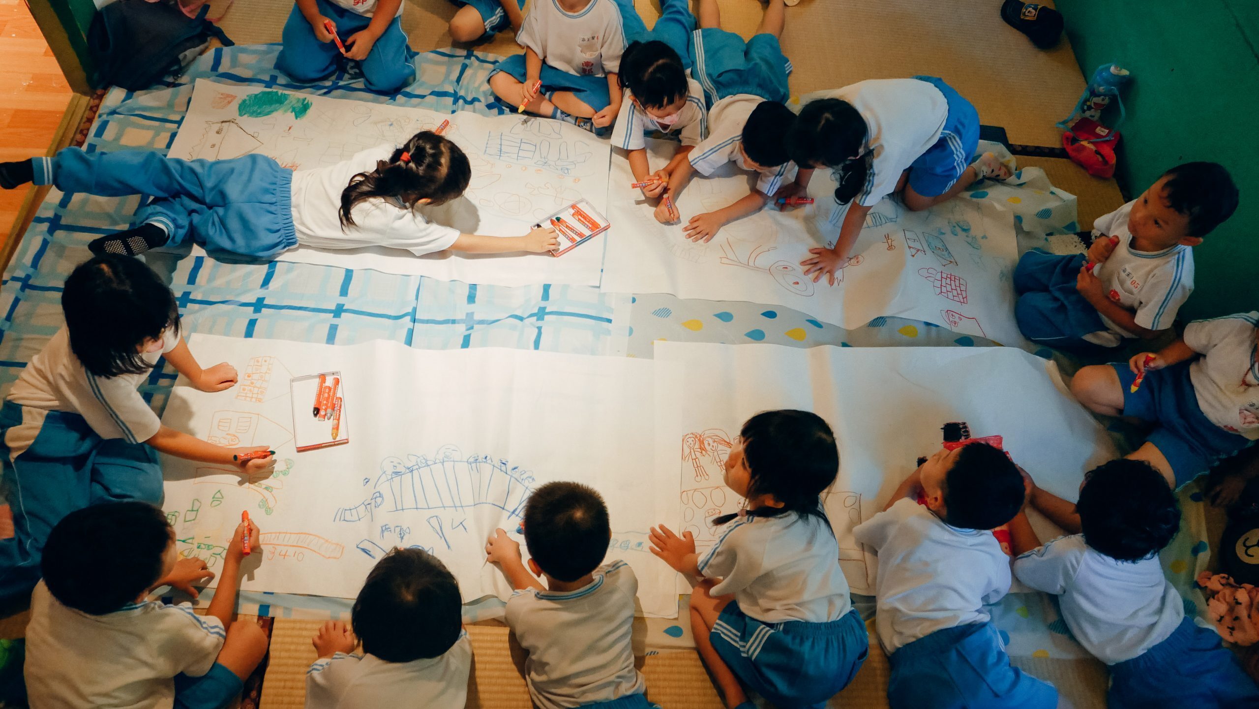 幼兒園小朋友以路上觀察為題趴在地上繪畫